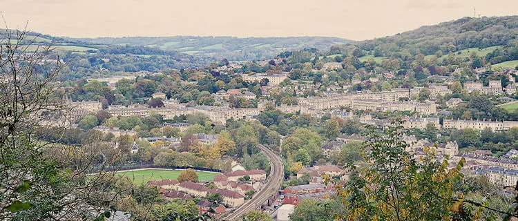 Landscape image of view from a high vantage point of the city of Bath showing the railway track leading in and out of the city.