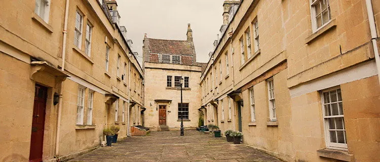 Short landscape wide photo of cul-de-sac row of terraced residential buildings in classic Bath building style.