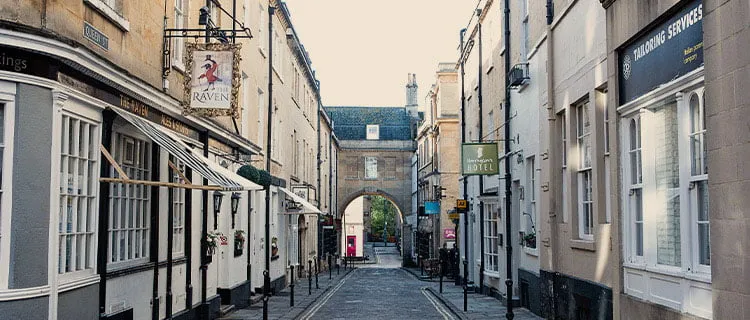 Views along a street with commercial buildings on either side with an arched walkway at the end of the street