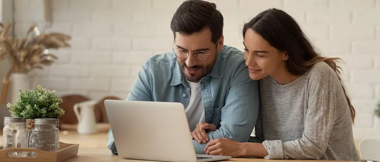 landscape image of a man and woman watching laptop screen in home