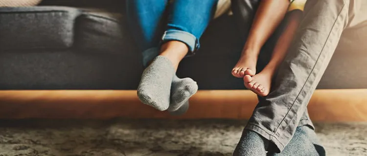 Landscape image of bottom of the sofa with parents feet and children's feet in shot