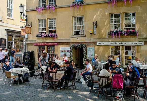 People sat at chairs and tables on a street in Bath